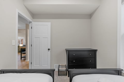 Interior view of a cozy bedroom with twin beds and a black dresser.