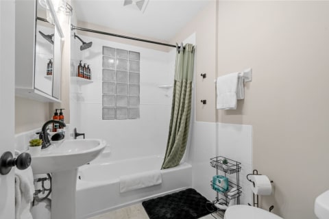 Compact bathroom featuring a bathtub, white walls, and modern fixtures.