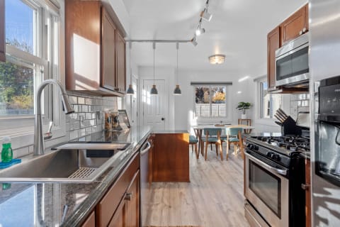 Modern kitchen with stainless steel features and a cozy dining area with wooden furniture.