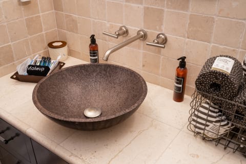 Stylish bathroom sink and countertop with makeup organizer, facial soap, and towels.