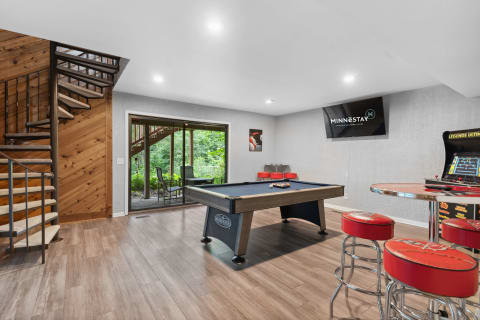 Interior of a game room featuring a pool table, arcade game, and a spiral staircase.