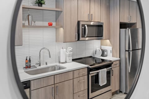 Modern kitchen with wooden cabinets, stainless steel appliances, and white countertops.