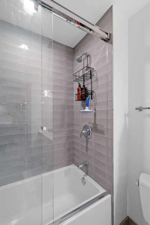Sleek bathroom shower area with gray tiles and a glass door.