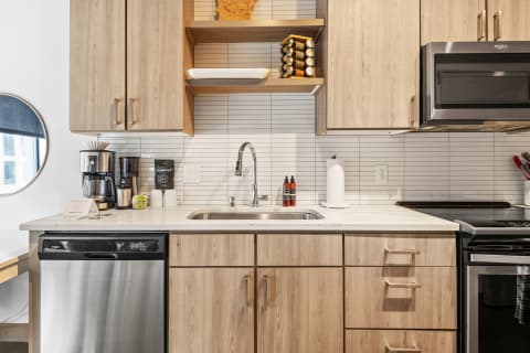 Modern kitchen with wooden cabinets, coffee maker, and stainless steel appliances.