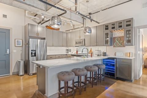 A contemporary kitchen with a marble island, gray cabinetry, and stainless steel appliances in an industrial setting.