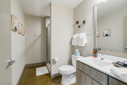 A clean, modern bathroom with beige walls, a glass shower, and contemporary fixtures.