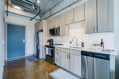 Contemporary kitchen featuring stainless steel appliances and light wood cabinets.