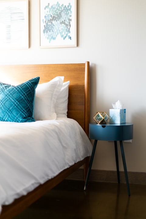 Cozy bedroom corner featuring a wooden bed, colorful pillows, and modern decor.