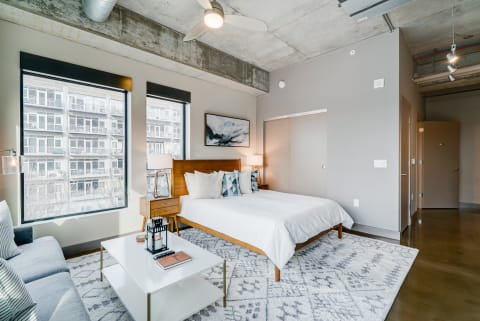 Modern bedroom with large windows, a king-sized bed, and stylish furnishings.