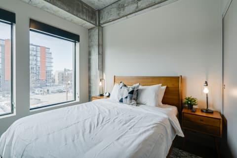 A cozy modern bedroom featuring a king-sized bed, large windows, and elegant decor.
