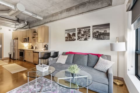 Modern living space with gray sofa and kitchen area.