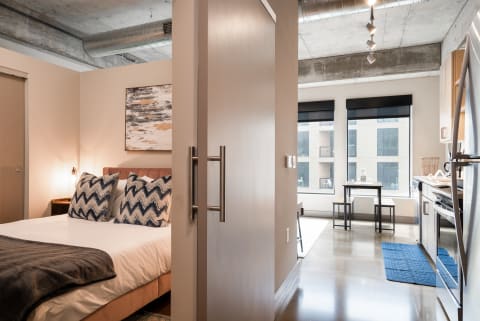 Interior view of a modern studio apartment showcasing a bed, dining area, and kitchen.