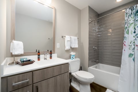 Modern bathroom with white sink, wooden cabinetry, and a floral shower curtain.