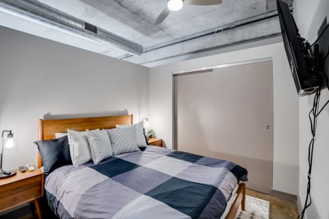 Modern bedroom with wooden bed frame, patchwork quilt, and minimalist decor.