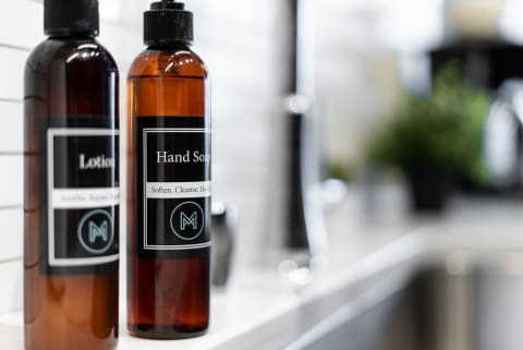 Bottles of hand soap and lotion on a countertop in a bathroom.
