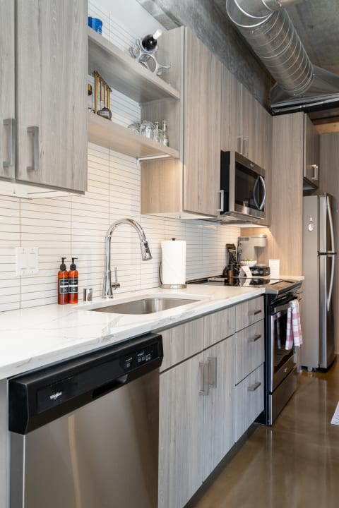 Stylish kitchen with wooden cabinets, white countertops, and stainless steel appliances.