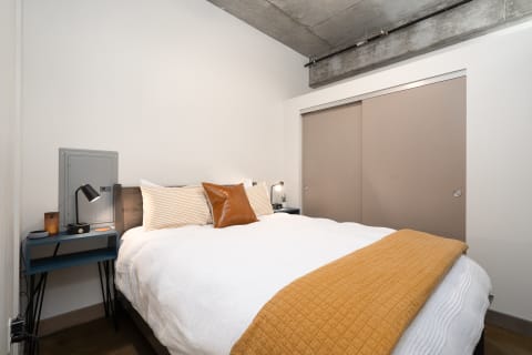 Modern bedroom with a queen-sized bed, nightstand, and sliding doors.