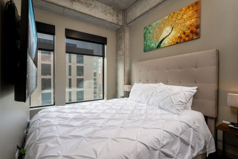 Contemporary bedroom featuring a white bedspread and abstract wall art.