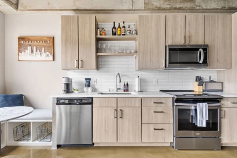 Modern kitchen featuring light wood cabinetry, stainless steel appliances, and a cozy dining nook.