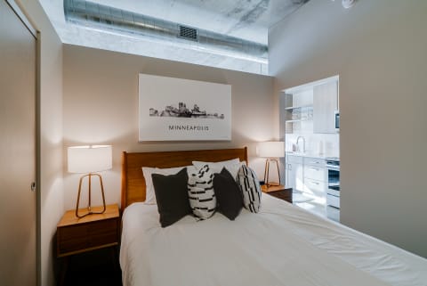Modern bedroom with a wooden bed, decorative pillows, and a lamp.