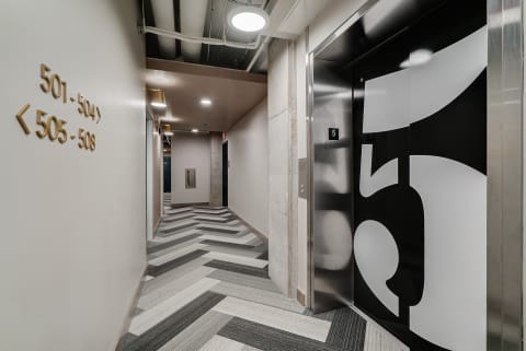 Interior hallway with elevator and room number signs in a contemporary style.