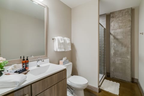 Modern bathroom with a large mirror, white fixtures, and a walk-in shower.