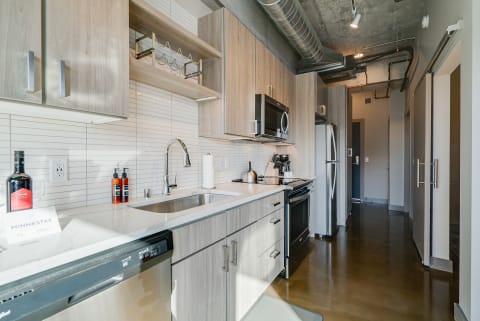 A contemporary kitchen with light wood cabinets and stainless steel appliances.