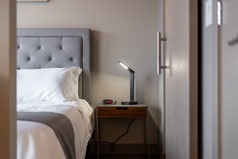 Modern bedroom with tufted grey headboard and black desk lamp.