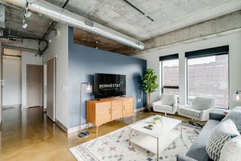 Modern living room with gray sofa, accent chairs, and a television setup.