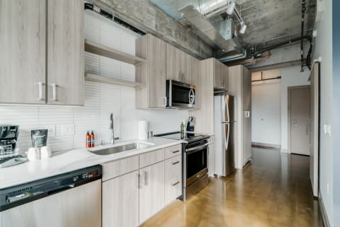 Contemporary kitchen with wood cabinets and sleek appliances, highlighting an industrial design.