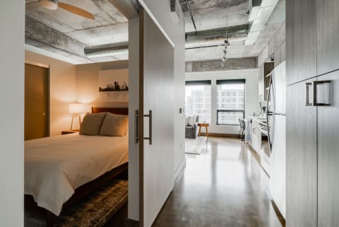 A view into a modern apartment showing a bedroom and living area with stylish furnishings.