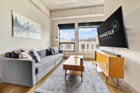 Modern living room with gray sectional sofa, abstract wall art, large TV, and wooden coffee table.