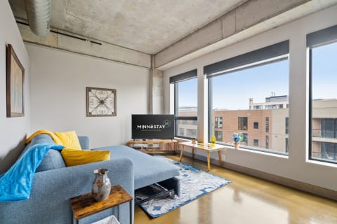 Modern living room with gray couch, large windows, and decorative elements.