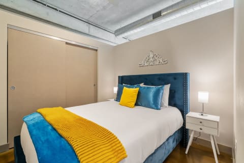 Cozy bedroom with blue headboard, white bedding, and a yellow throw blanket.