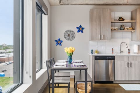 Modern kitchen with a dining table, yellow tulips, and blue floral wall decorations.