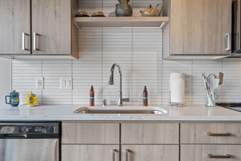 Modern kitchen sink with marble countertop and decorative items.