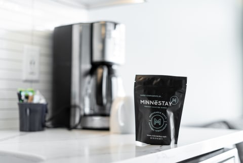 Black coffee bag from Minnestay on a marble countertop in a minimalist kitchen.