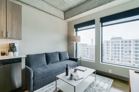 Modern living room with gray sofa, white coffee table, and large windows.