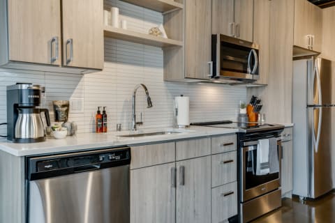 Contemporary kitchen featuring light wood cabinets, a Keurig coffee maker, and stainless steel appliances.