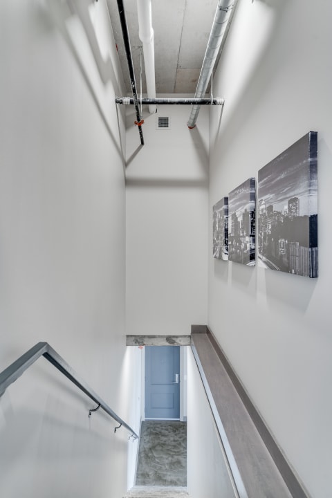 Modern stairwell with white walls and cityscape artwork.