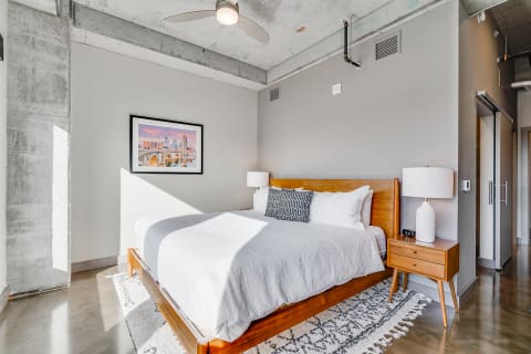 Modern bedroom featuring a wooden bed, gray walls, and natural light.