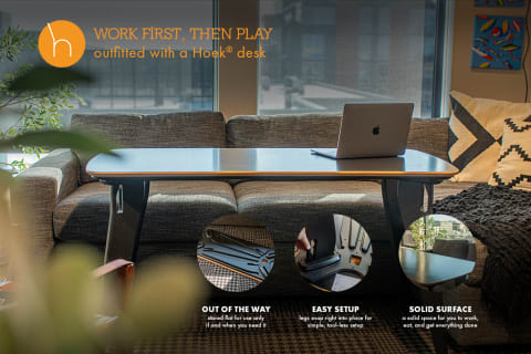A Hoek® desk set up in a cozy living area, featuring a MacBook and stylish couch.
