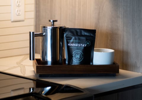 Stylish coffee arrangement with a French press, coffee bag, and white cup on a wooden tray.