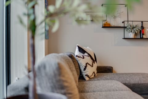 A gray sectional couch with a black and white geometric pillow in a cozy living room.