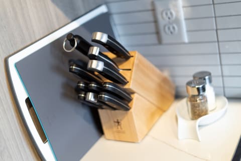 A wooden knife block with knives, a grey cutting board, and salt and pepper shakers on a kitchen countertop.