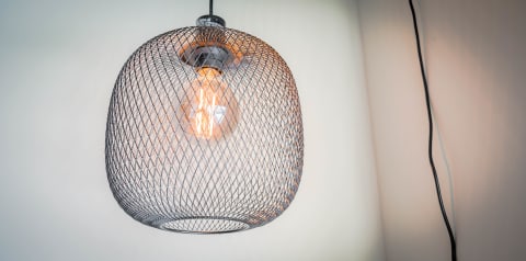 A contemporary pendant lamp with a mesh shade and a glowing filament bulb.