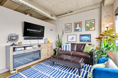 Cozy living room featuring a leather sofa, TV, and colorful artwork.