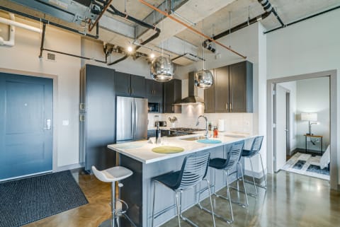Stylish modern kitchen featuring an island with bar stools, stainless-steel appliances, and industrial pendant lights.