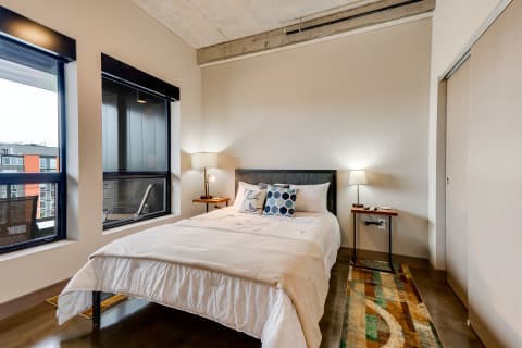 Contemporary bedroom with a queen-sized bed, large windows, and stylish furnishings.