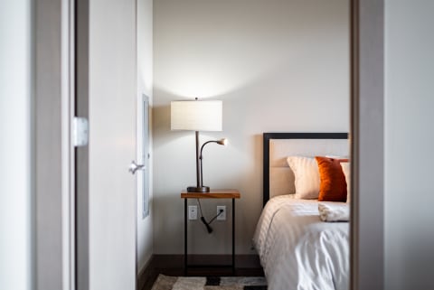 View of a modern bedroom with a lamp and a neatly made bed.